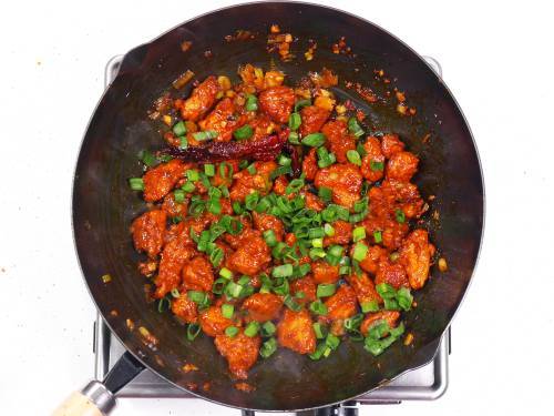 garnishing szechuan chicken with spring onions