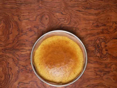 cooling baked eggless orange cake in pan