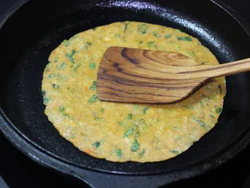 press down the vegetable paratha with a spatula