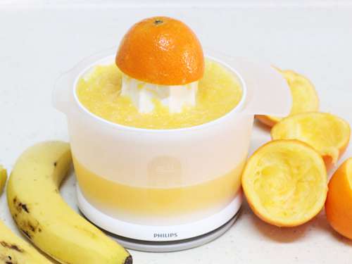 making orange juice in a juicer