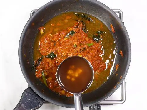 pouring tamarind water to make coconut salmon curry