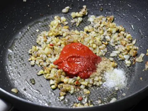 adding red chilli paste to golden onions for schezwan noodles