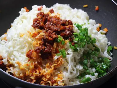 adding noodles, sauce and green onions