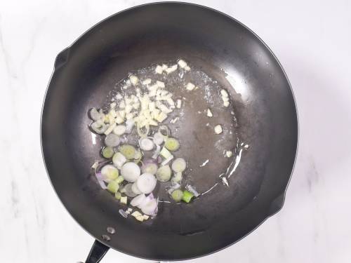 frying spring onions in oil to make hakka noodles