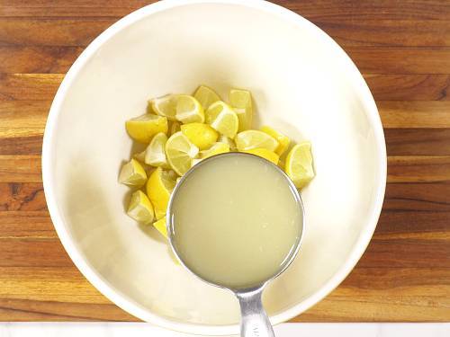 adding lemon pieces and lemon juice to a bowl