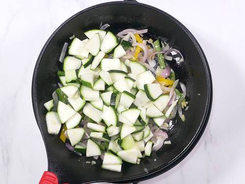 frying zucchini on a black pan
