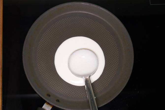 spreading dosa batter on the griddle