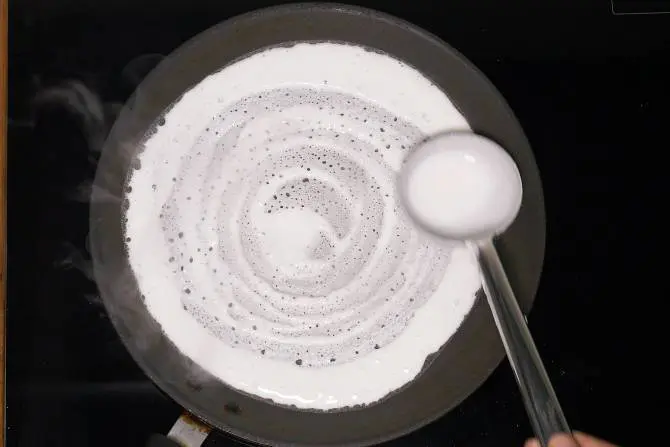 spreading batter on a hot griddle to make dosa