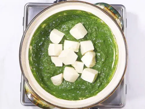 adding paneer to prepares palak