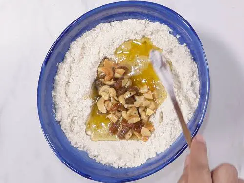 mixing dry ingredients with ghee and nuts with a spoon