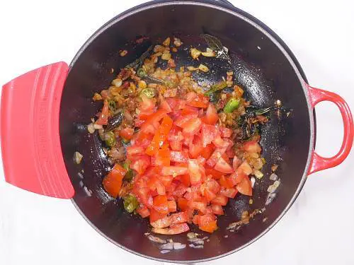 adding tomatoes to the pan