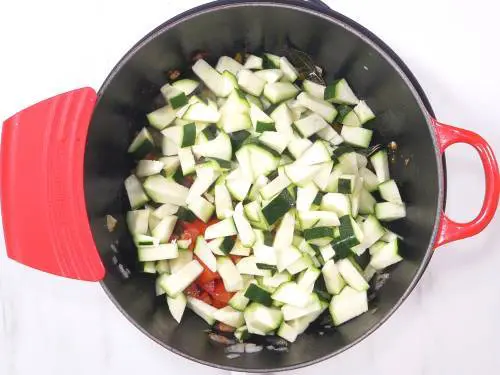 adding zucchini to the pan to make curry