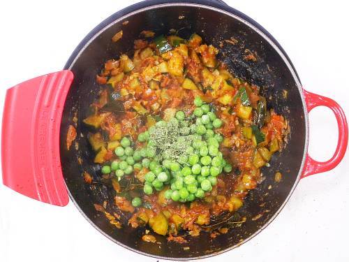 adding peas to make zucchini curry