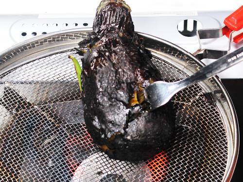 inserting fork into the grilled eggplant for bharta