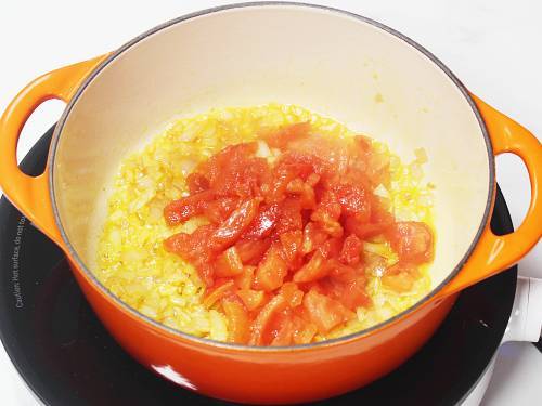 adding chopped tomatoes to sauteed onions