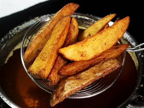 double fried crispy potato wedges in a skimmer