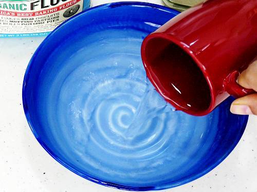 pour warm water to a mixing bowl to make pizza dough