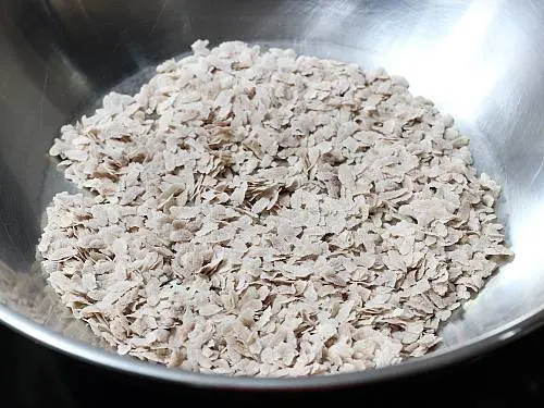 roasting brown poha in a pan to make chivda