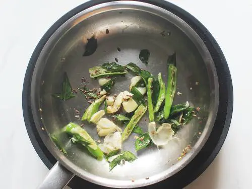 fry garlic curry leaves and chilies in pan