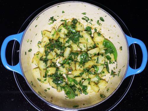 stir frying aloo and methi leaves in a pan