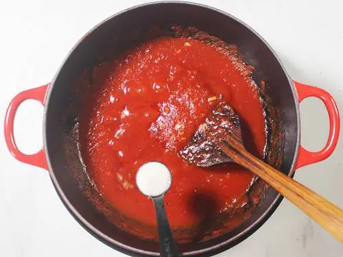 sugar and salt being added to pizza sauce