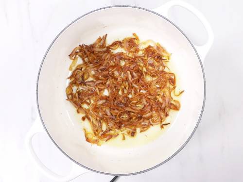 caramelized onions in a white dutch oven for vegetable biryani