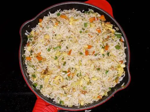 stir frying egg fried rice in a pan