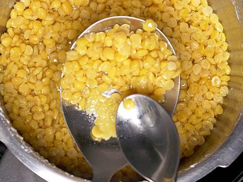 fully cooked Bengal gram dal getting mashed in a pressure cooker