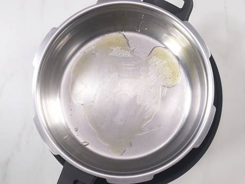 heat ghee in a cooker to make pongal