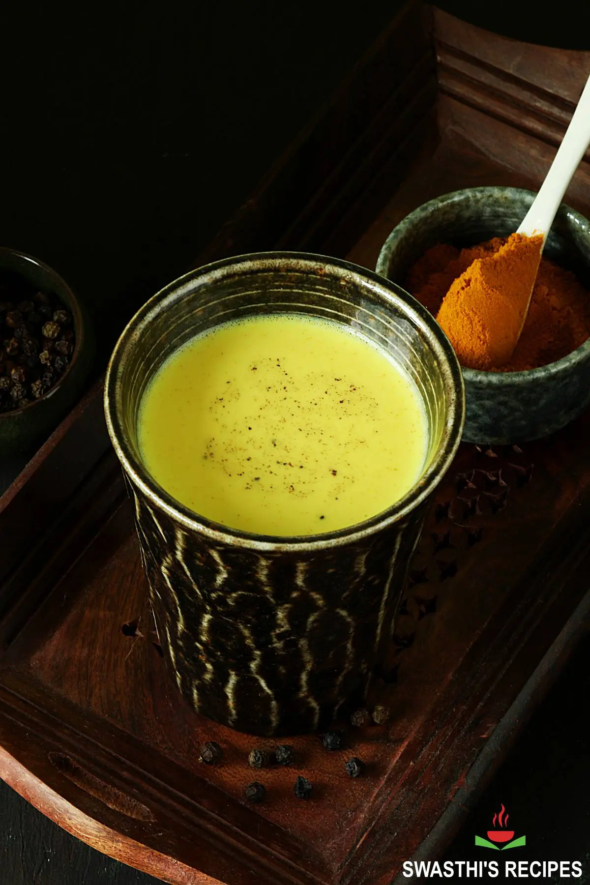 Turmeric milk also known as Haldi doodh served in a black glass