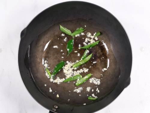 frying garlic chilies and curry leaves in a wok