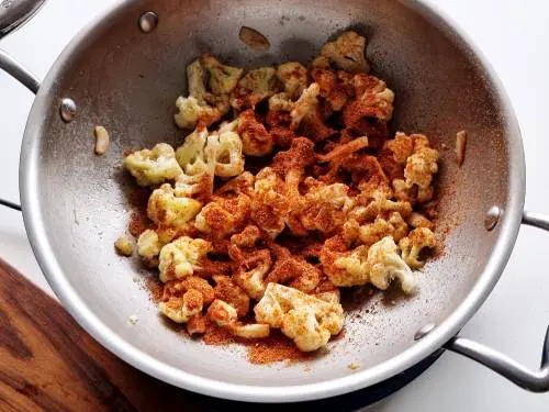 sprinkle spices on cauliflower stir fry