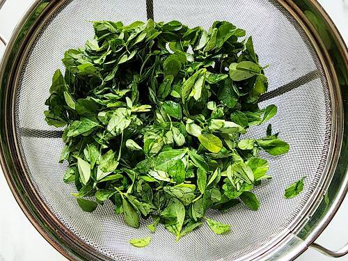 Methi Leaves left to drain in a colander