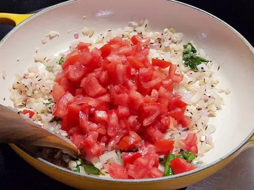 adding tomatoes to make brinjal curry
