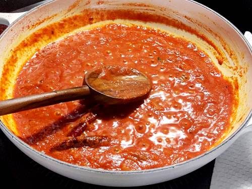 cooking tomatoes with spices to make paneer jalfrezi