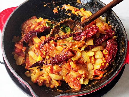 sauteed onions and tomatoes with spices in a pan