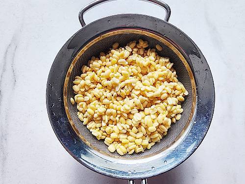 soaked moon dal in a strainer