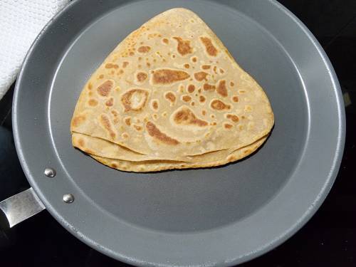 flaky triangle parathas cooking on a pan