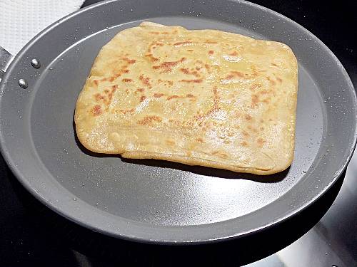 frying layered square paratha in a pan