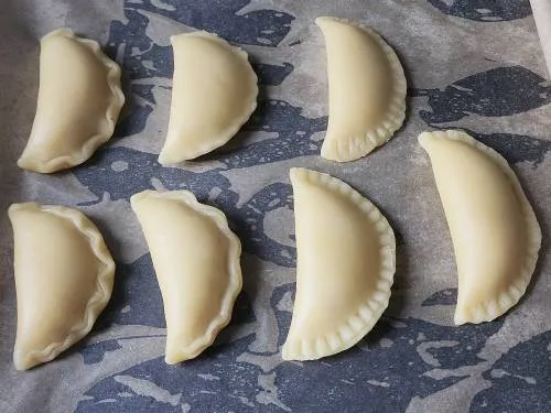 shaped gujiya on a baking tray ready to fry