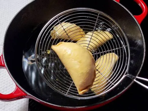 fried gujiya on a spider spoon