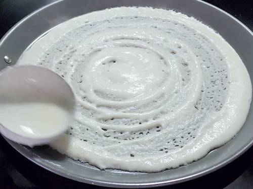 spreading batter on a tawa